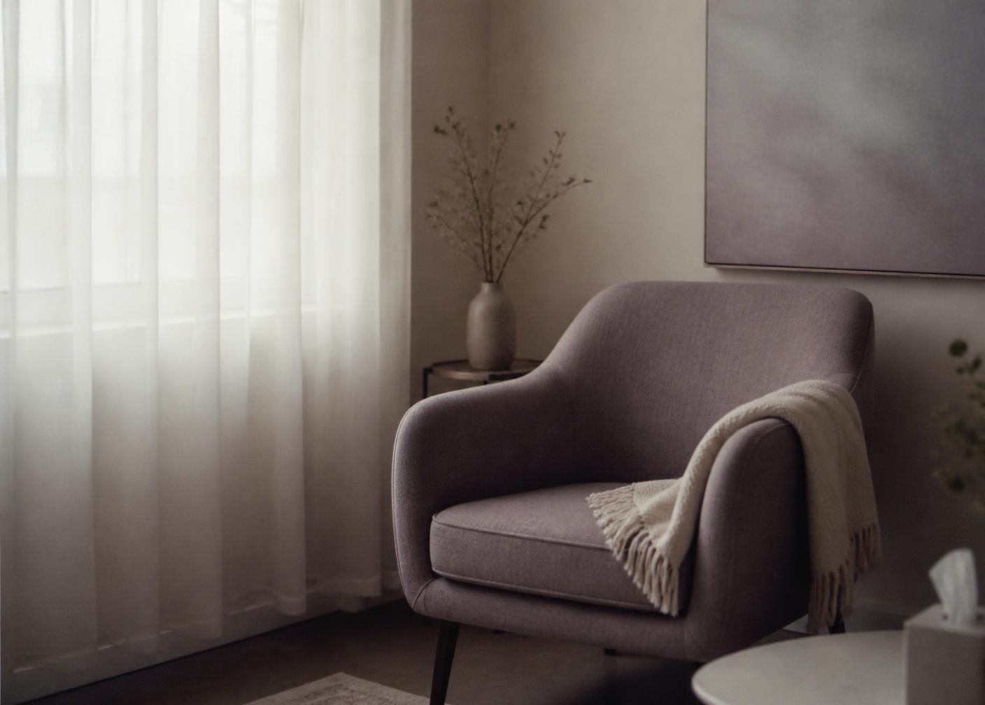 Calm therapy room with an upholstered chair beside a softly lit window
